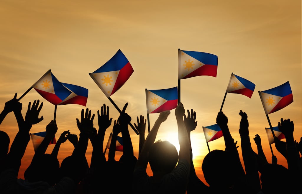 Group of People Waving Filipino Flags in Back Lit